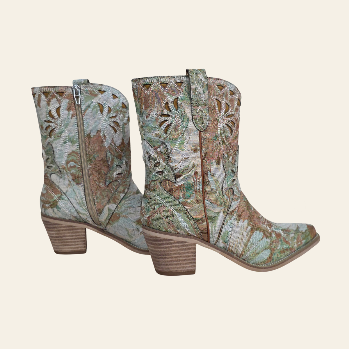 A pair of western-style ankle boots with a floral woven pattern in muted green, beige, and brown tones, featuring a stacked wood-look heel and side zipper - The Amaryllis