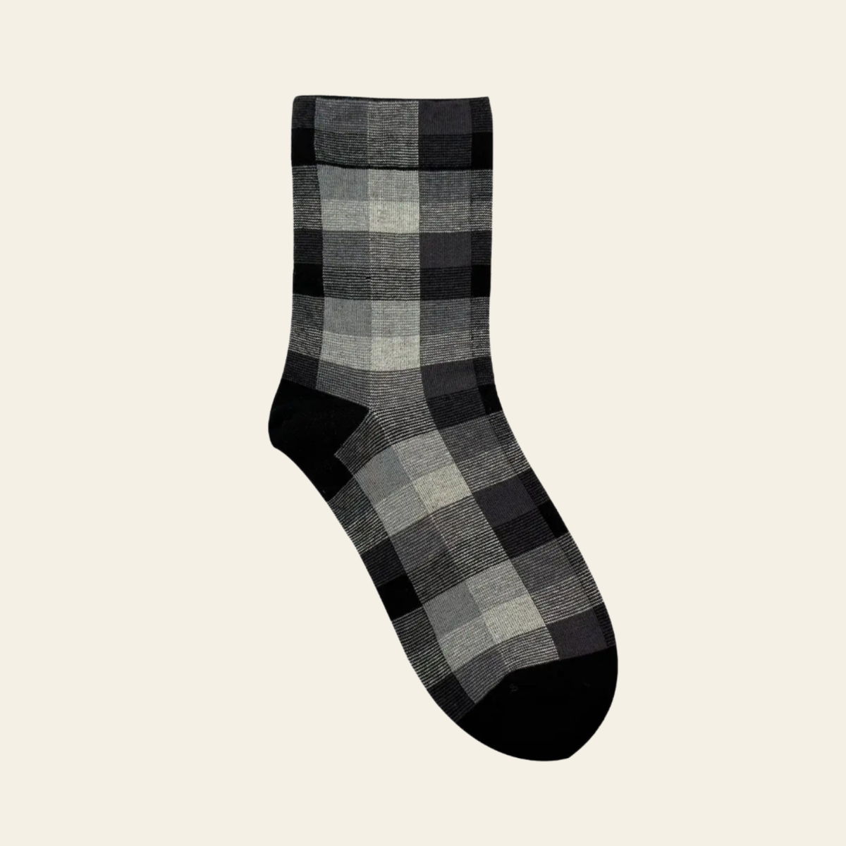 A single crew sock with a gray, black, and white plaid pattern, shown against a solid light beige background.