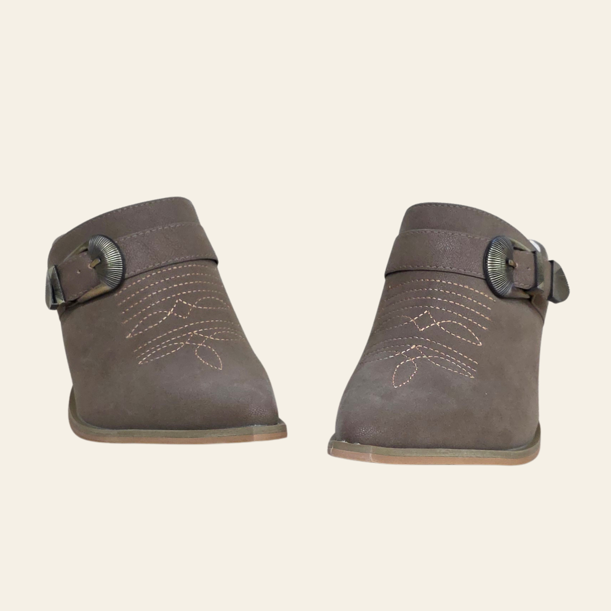 A pair of women's taupe-brown suede ankle boots with decorative contrast stitching and a buckle strap detail, shown against a solid cream background.