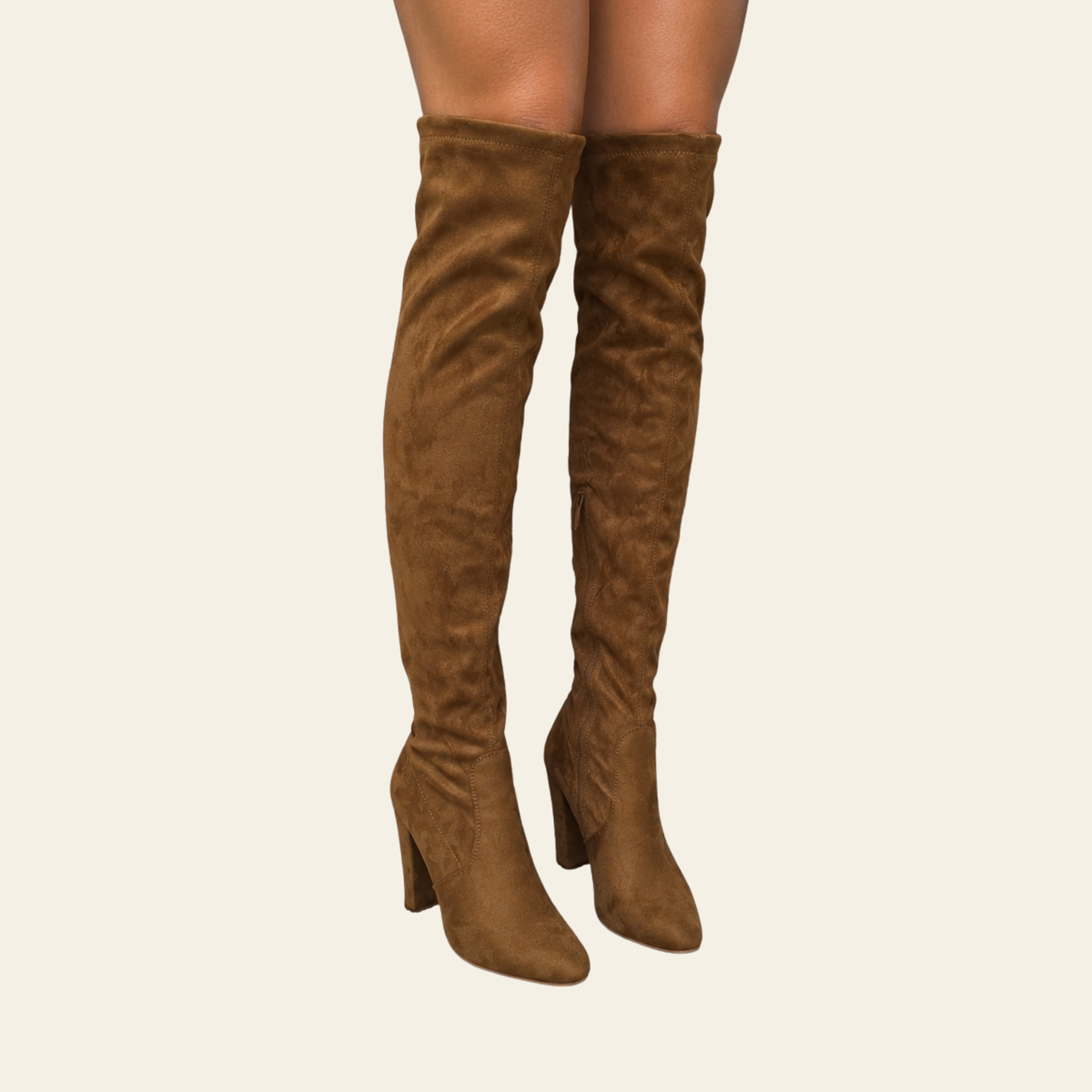 A pair of brown suede over-the-knee boots with block heels, shown on a model's legs against a light beige background.