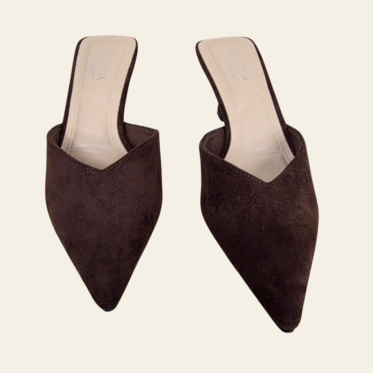 A pair of dark brown suede pointed-toe mule heels on a light cream background. The shoes feature a slingback design and are shown from a top-down angle.