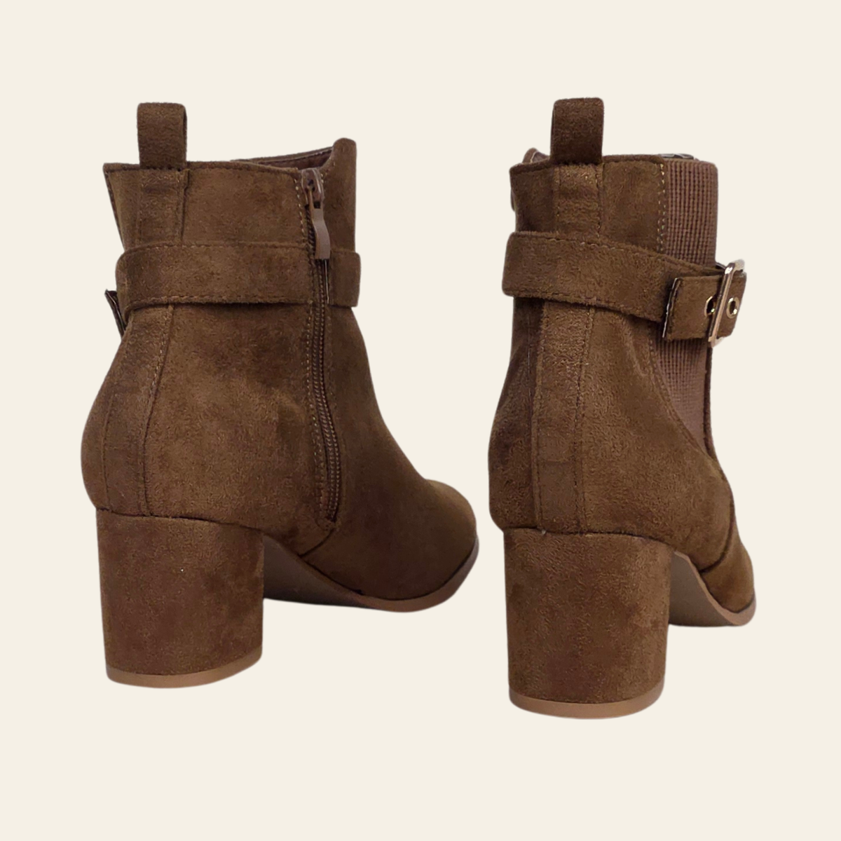 A pair of women's brown suede ankle boots with block heels, side zippers, and buckle-strap details, shown from the back on a light cream background.