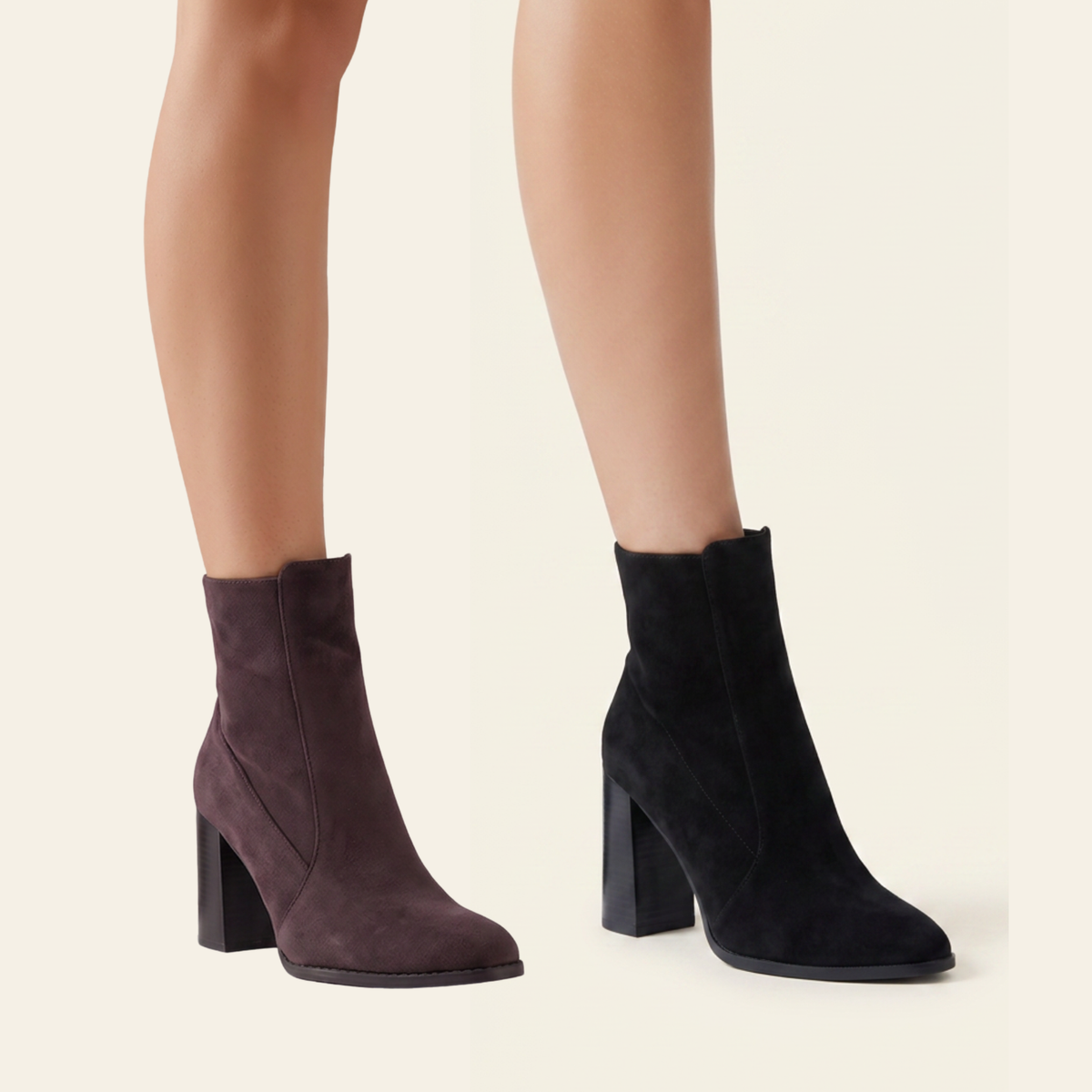 A pair of ankle-height block-heel boots in dark suede, shown on a model's feet against a light beige background. One boot is a muted plum-brown and the other is black.