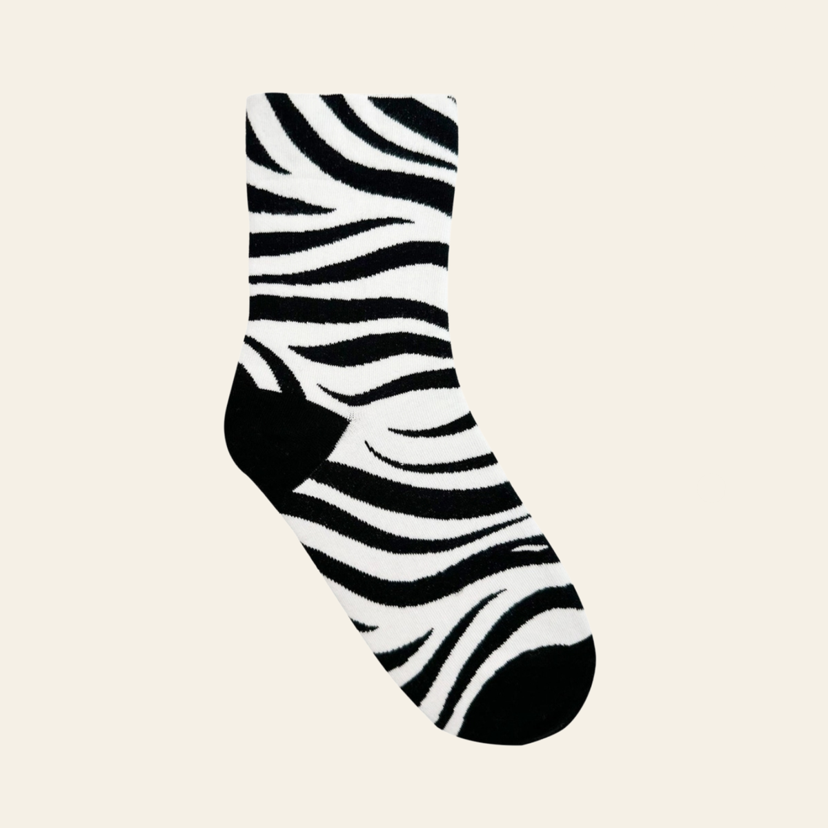 A single crew sock with a bold black and white zebra stripe pattern, featuring solid black heels and toes.