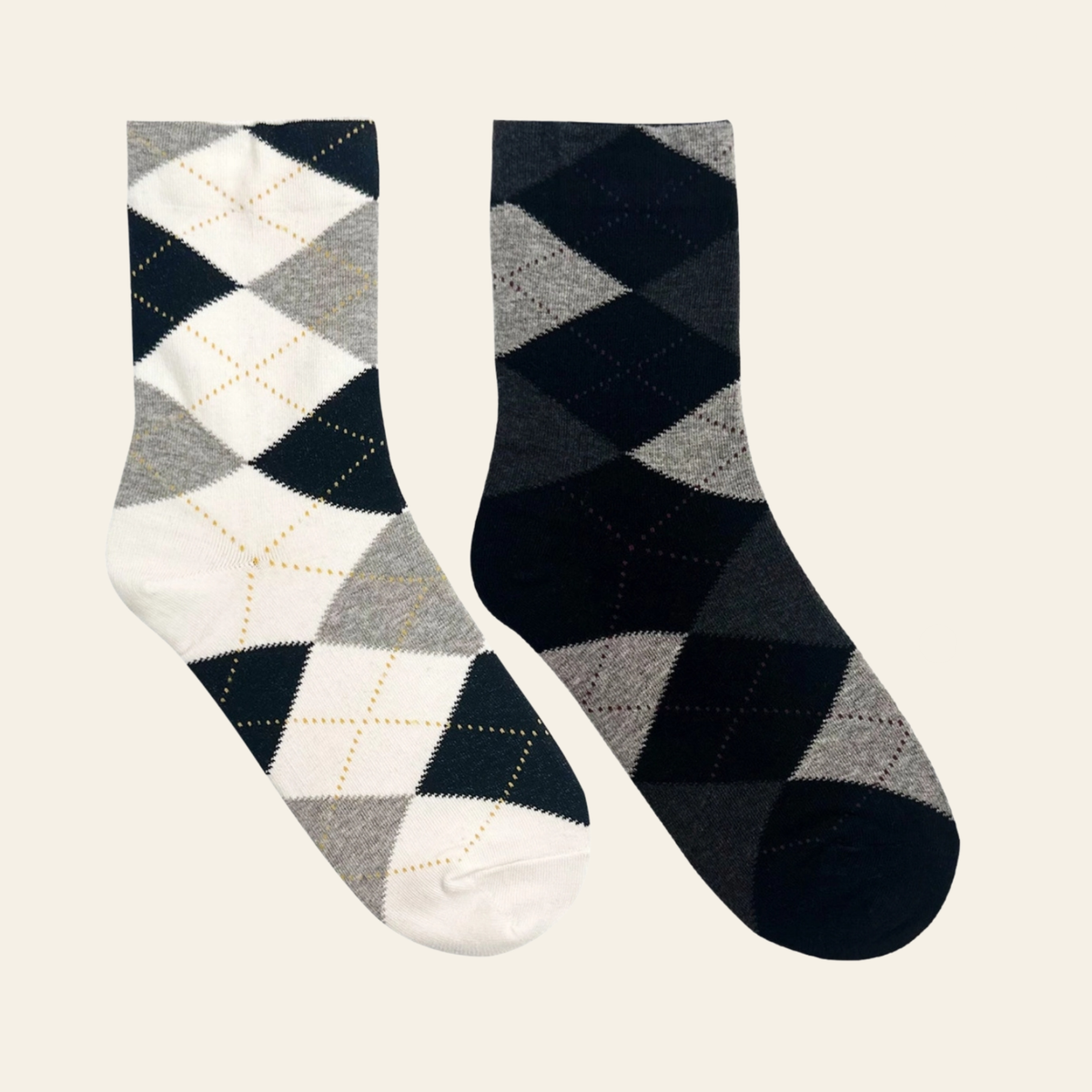Two pairs of argyle socks displayed side by side on a light white background. One pair features a white, gray, and black argyle pattern with thin gold dotted lines, and the other pair features a black, gray, and white argyle pattern.