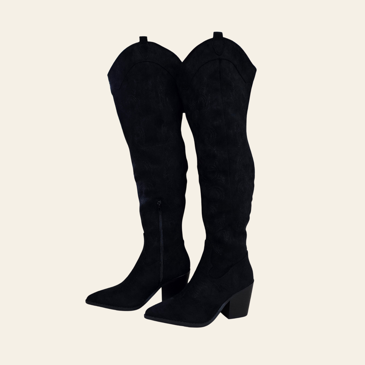 A pair of black suede over-the-knee boots with a low block heel and pointed toe, shown against a solid light beige background.