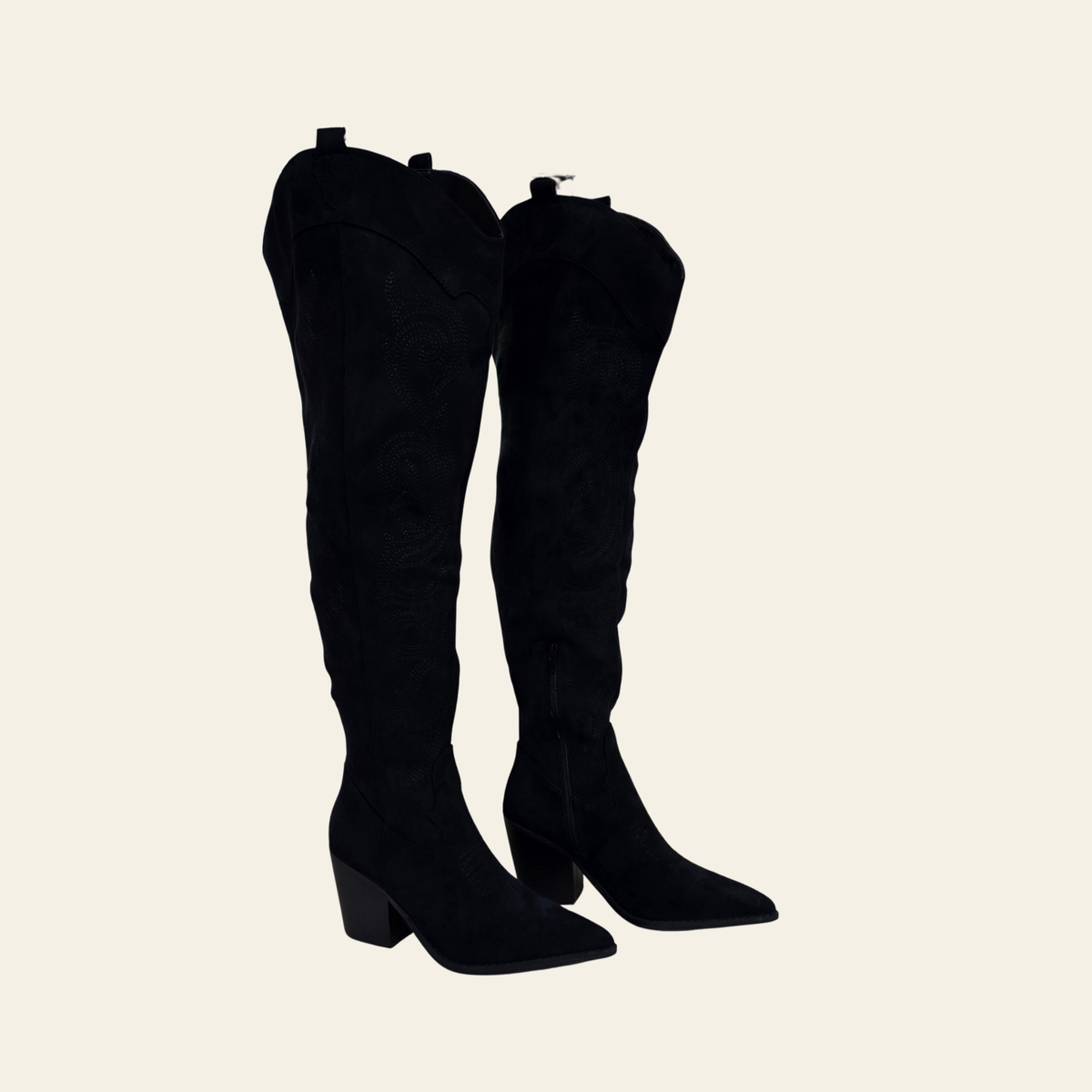 A pair of black suede over-the-knee boots with pointed toes and low block heels, shown against a solid light beige background.