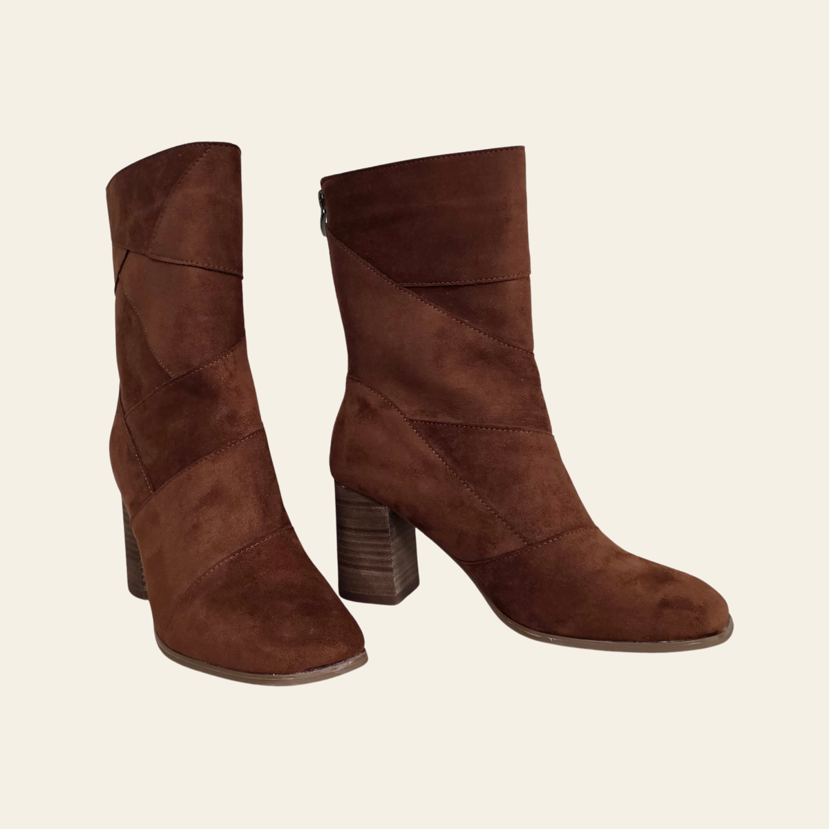 A pair of brown suede ankle boots with block heels, shown from the side against a light cream background.