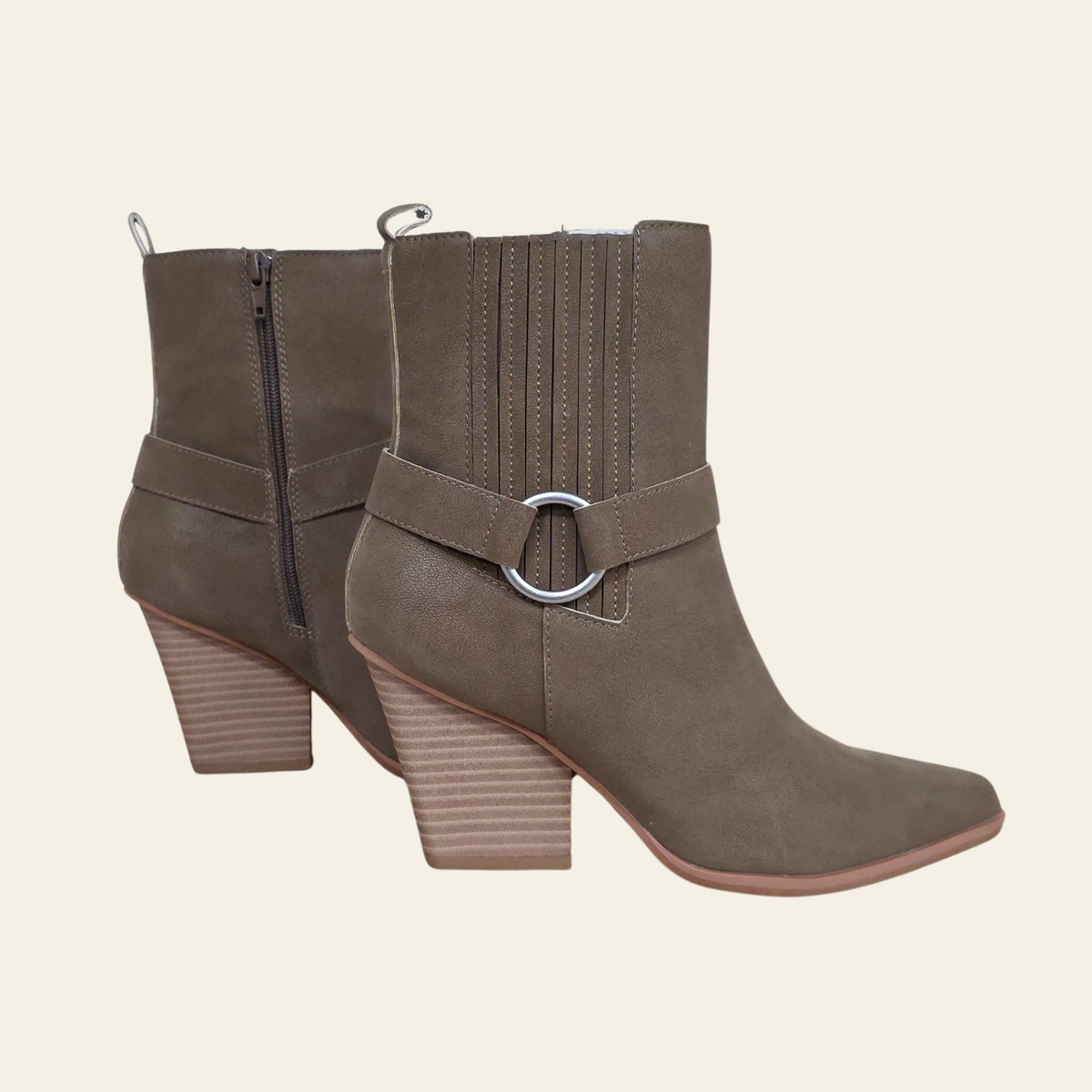 A pair of taupe-brown suede ankle boots with a side buckle strap and block heel, shown against a solid light beige background.