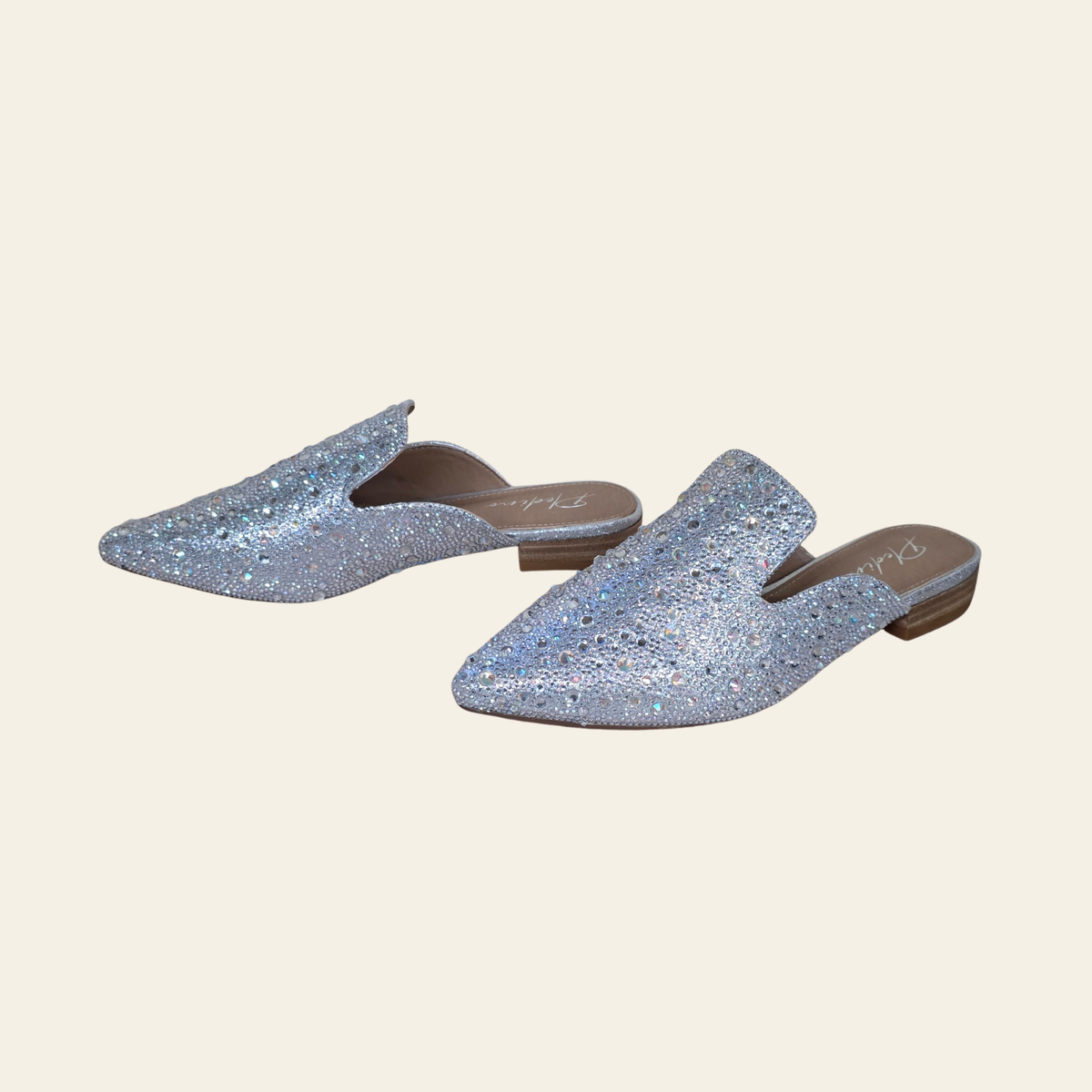 A pair of Plendino GEM pointed-toe mule flats covered in rhinestones, shown on a solid cream background.