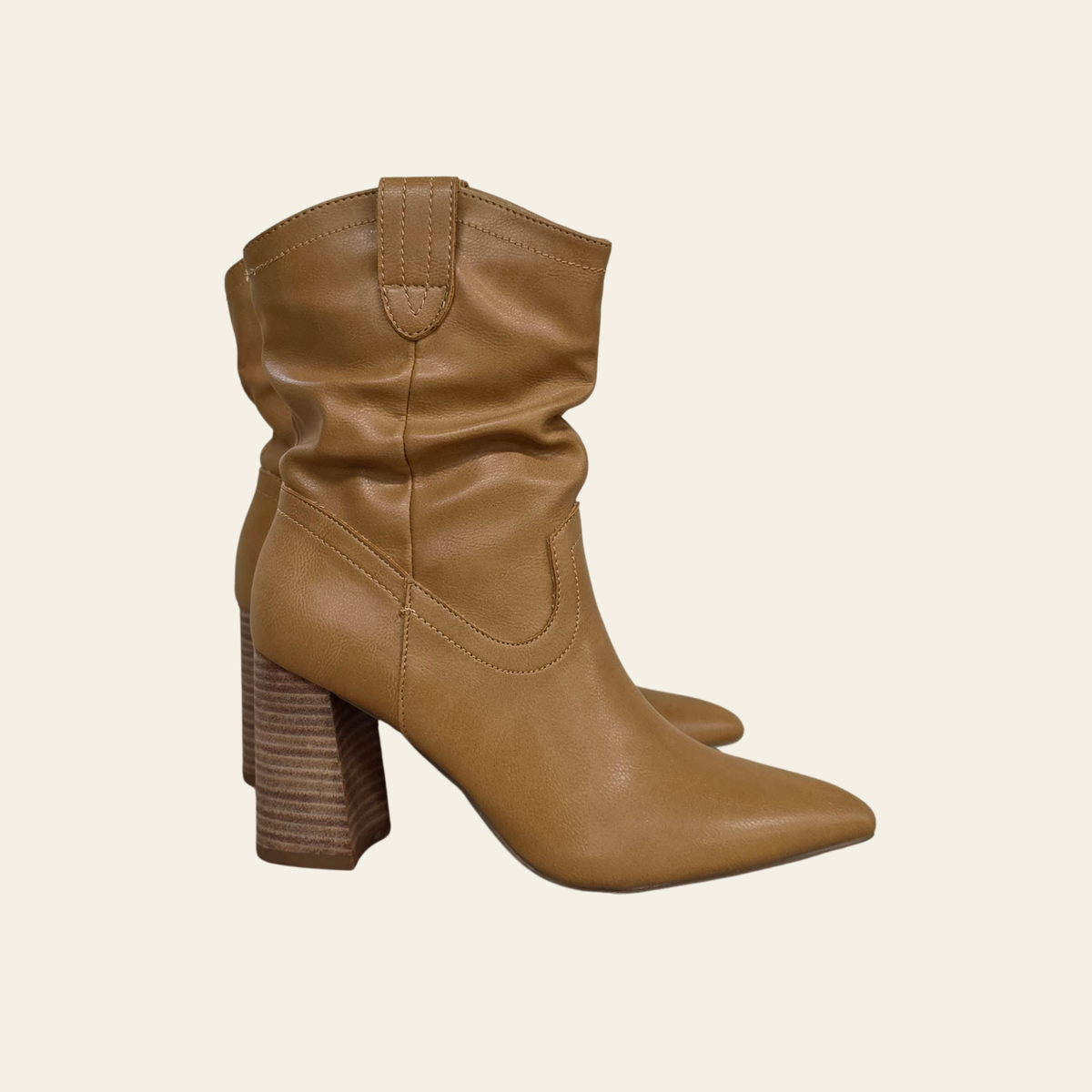 A pair of tan faux leather slouchy ankle boots with pointed toes and stacked block heels, shown against a solid off-white background.