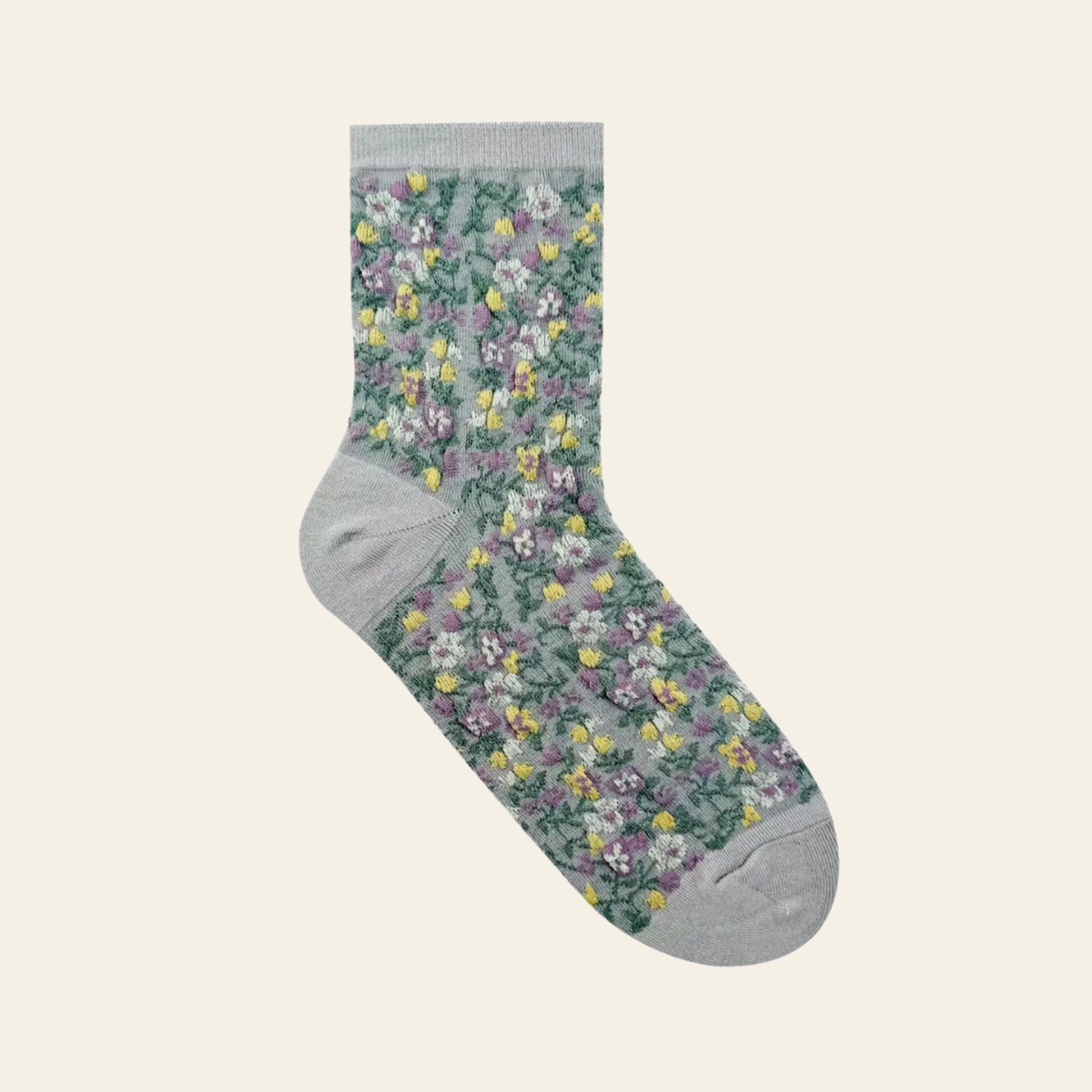 A single crew sock with a dense small floral print in green, purple, yellow, and white on a light gray base, shown against a plain light beige background.