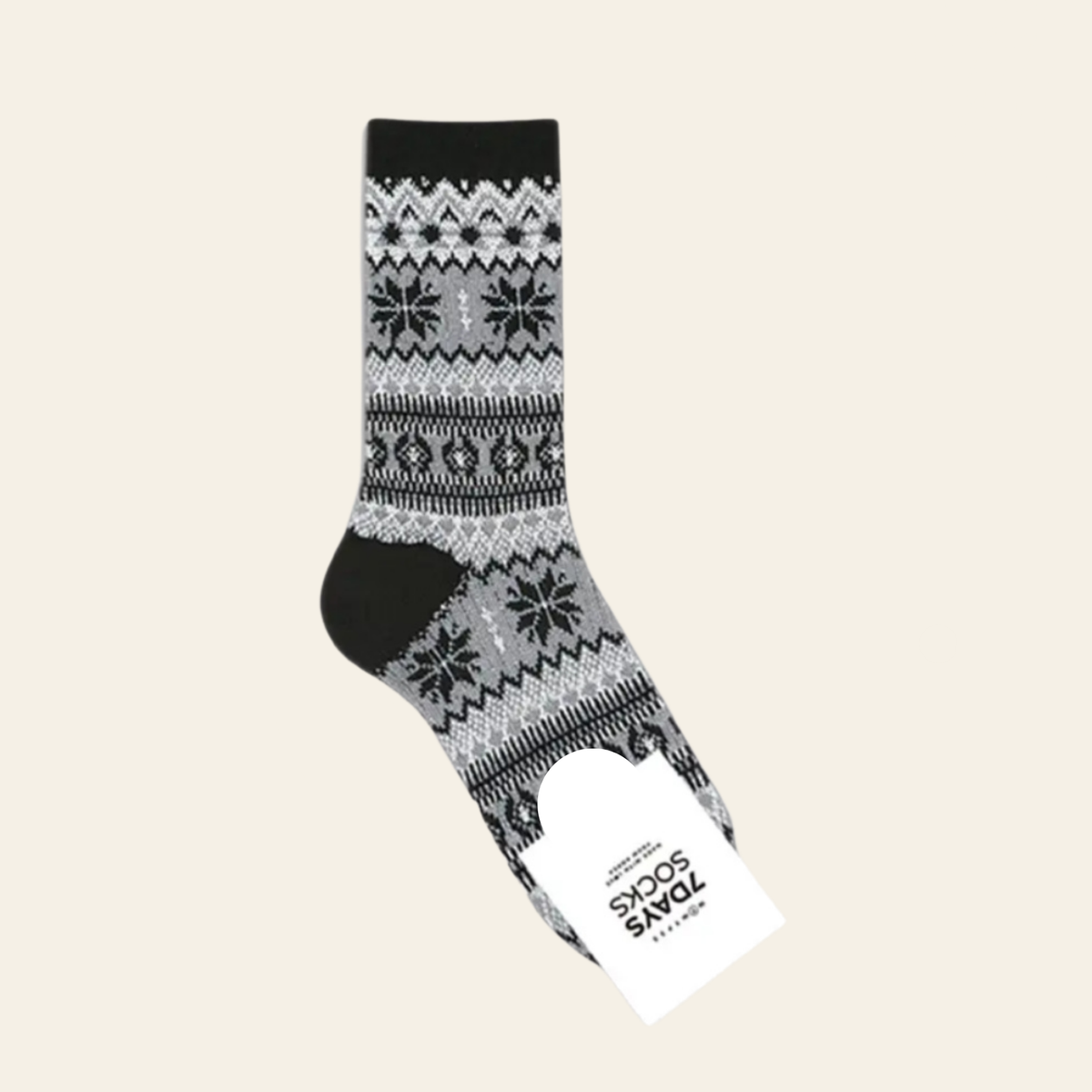 A single crew sock with a black and gray Nordic fair isle pattern, shown with its white paper tag attached against a solid light beige background.