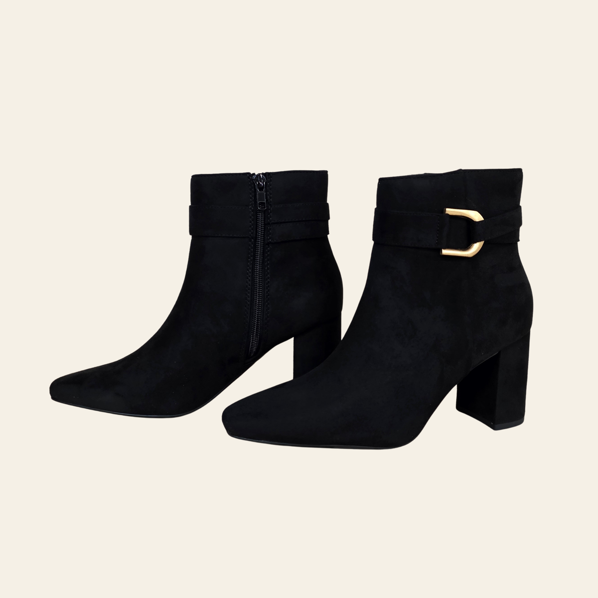A pair of black faux suede ankle boots with block heels, featuring a decorative strap with a gold buckle on the outer side and a side zipper.