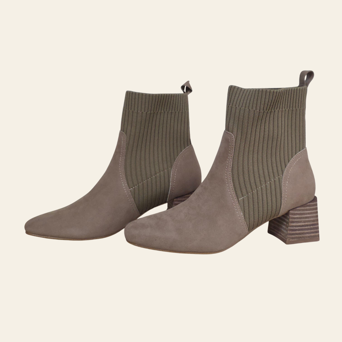 A pair of women's ankle boots in taupe suede and ribbed knit, featuring a low block heel, shown against a solid light beige background.