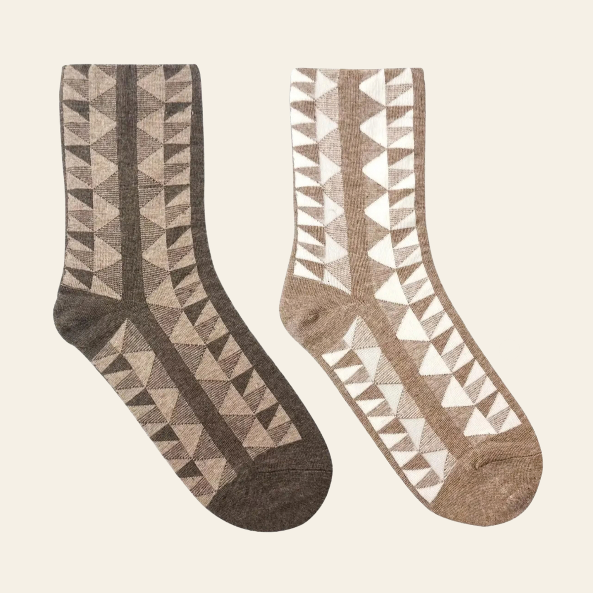 Two pairs of patterned crew socks displayed side by side on a light cream background. The left pair features a geometric triangle pattern in dark brown and beige.