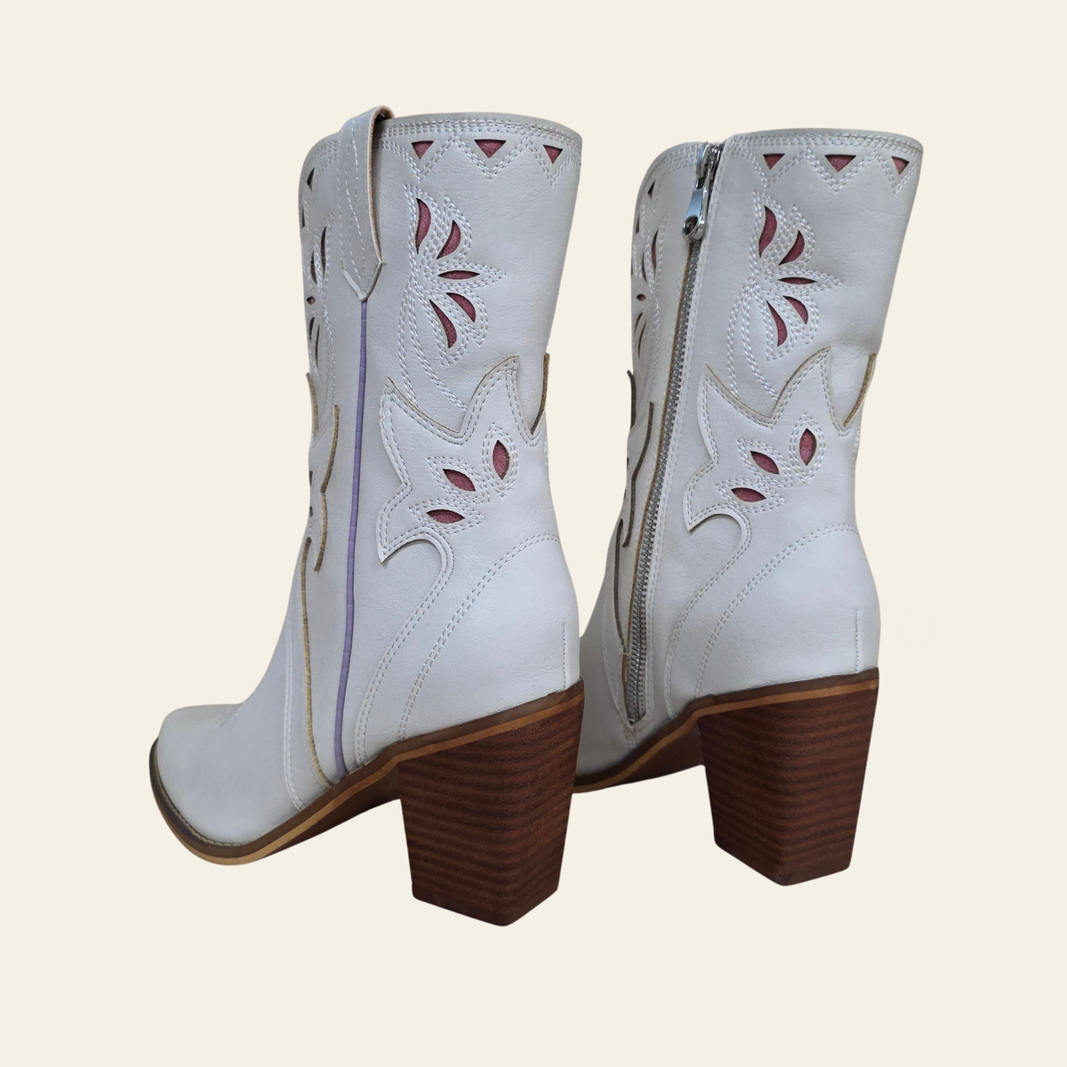 A pair of white western-style cowboy boots with brown block heels, shown from the back on a light beige background.