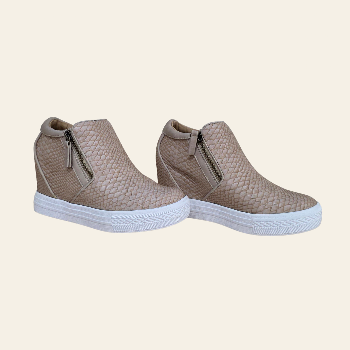 A pair of women's ankle-high slip-on sneakers with a textured, woven-look upper in a blush color and white soles, shown against a solid cream background.