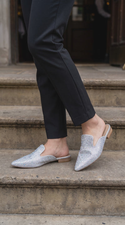 Plendino Gem rhinestone embellished mules on a model going down stairs.